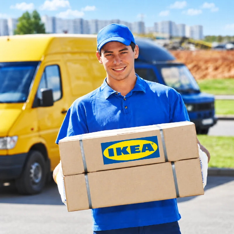 Delivery worker holding IKEA boxes in front of delivery vans